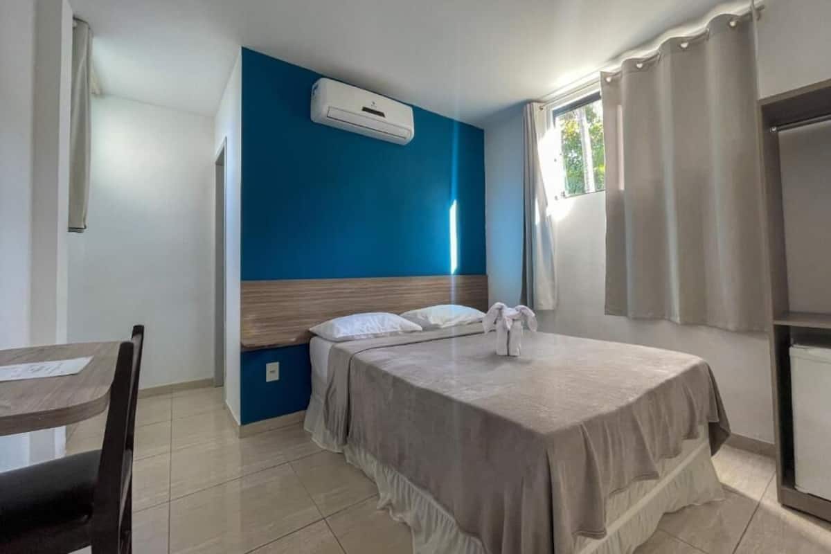 A hotel room with a bed, a desk, and a window with curtains.