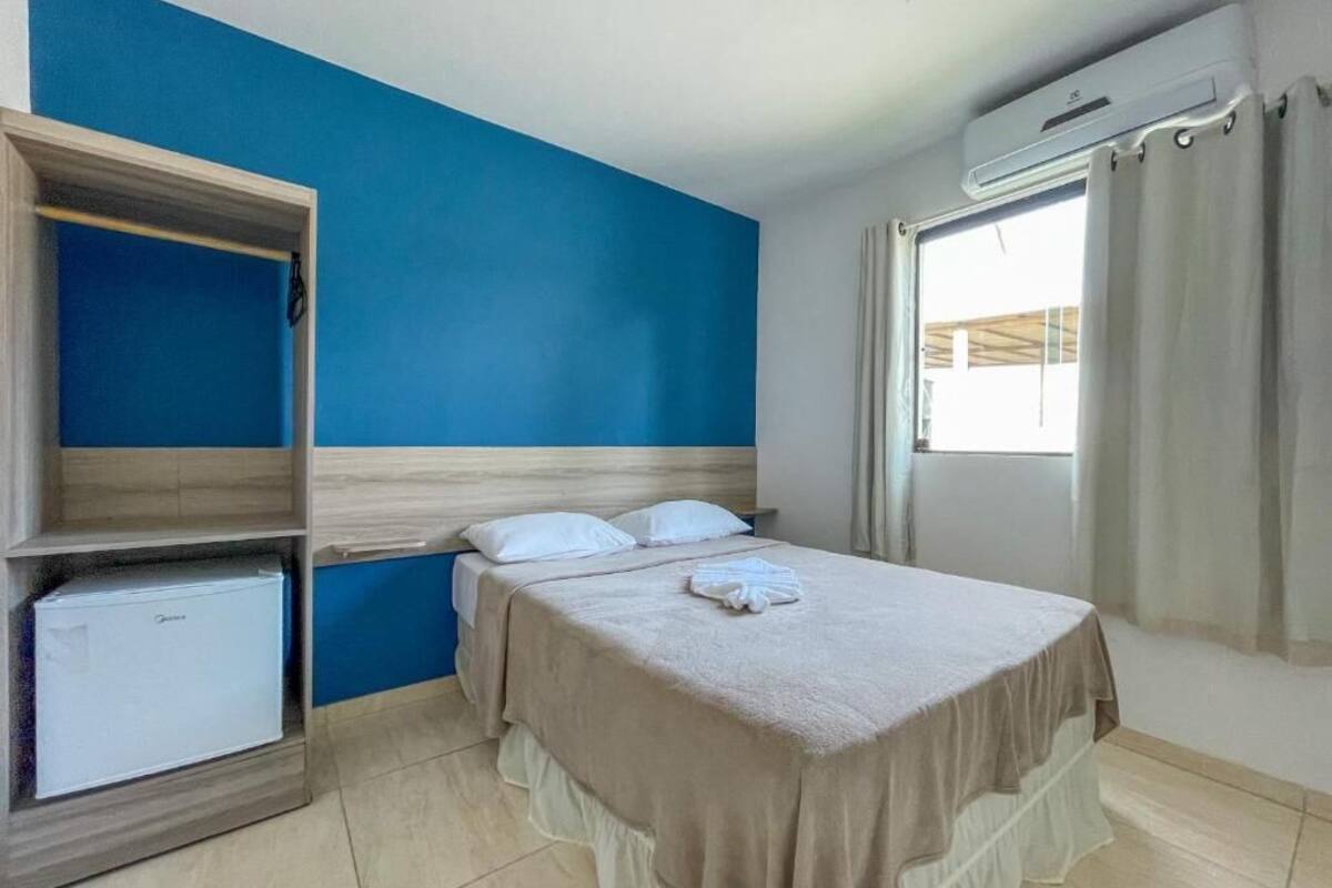 A hotel room with a bed, a wardrobe, and a window with curtains.