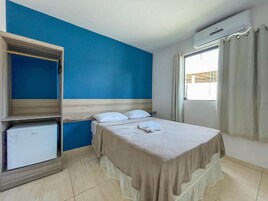 Una habitación de hotel con cama, armario y ventana con cortinas.