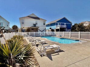 Zona residencial con piscina, cercas blancas y casas.