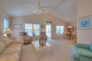 A spacious living room with a ceiling fan, a dining area with a table and chairs, and a view of the outside. - Stay at Reel Estate, a spacious 3-bedroom home in Oak Island, perfect for beach lovers! (Oak Island)