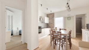 A modern kitchen with white cabinets, a dining table with chairs, and a hanging light fixture. - 3306 Villino Terracielo su Barbarhouse (Porto Cesareo)