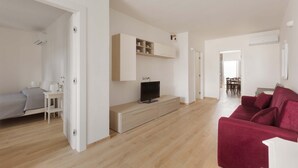 A modern living room with a TV, a red sofa, and a wooden cabinet. - 3306 Villino Terracielo su Barbarhouse (Porto Cesareo)