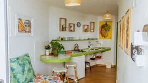 A compact kitchen with a green countertop, a dining area with a floral sofa, and a small bar area. - Apartment 302 Vista al mar "guest Friendly" (Cartagena de Indias)