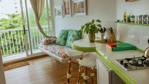 A kitchen with a green-tiled countertop, a stove, and a dining area with a bench and stools. - Apartment 302 Vista al mar "guest Friendly" (Cartagena de Indias)