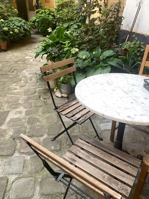 A patio with a round marble table and wooden benches.