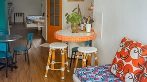 Un espace de vie compact comprenant un coin repas, un canapé agrémenté de coussins à motifs et un coin cuisine visible au fond.