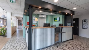 A reception desk with a modern design, a clock, and a digital display on the wall.