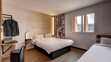 Een hotelkamer met een bed, een bureau met een laptop, een stoel en een raam met uitzicht.