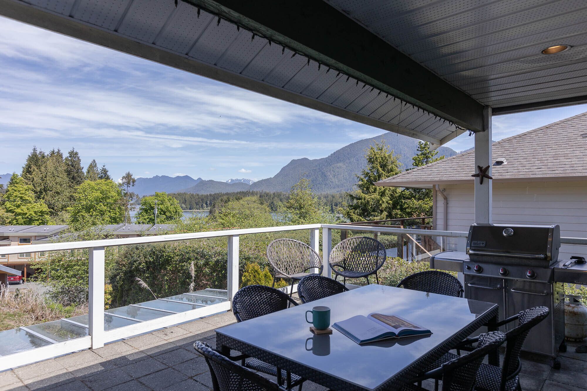 Une terrasse couverte avec une table, des chaises et un barbecue.