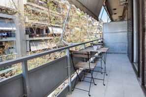 Ein Balkon mit Metallgeländer, einem Holztisch und einem Metallstuhl.