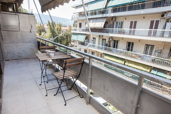 Ein Balkon mit Tisch und Stühlen, mit Blick auf ein mehrgeschossiges Gebäude mit Balkonen.