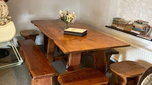 Un coin repas chaleureux avec une table en bois, des bancs et un tapis.