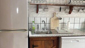 Une cuisine avec un réfrigérateur blanc, des armoires en bois, un plan de travail en granit, un évier et un lave-vaisselle.