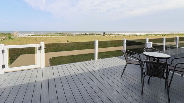 A deck with a view of the beach, a table, and chairs. - Bonny Bay (Bridlington)