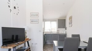A modern living room with a flat-screen TV, a wooden coffee table, and a dining area with a glass table and grey chairs. - Bonny Bay (Bridlington)