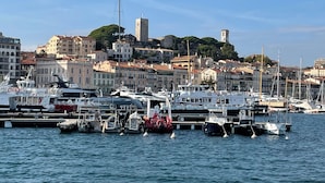 A marina with boats docked, surrounded by buildings and a hill with a tower. - Beautiful 2-BR flat + terraces - Cannes centre - 7CV3 (Cannes)