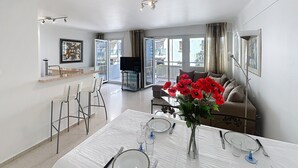 A modern apartment with a dining area, a living room with a sofa and a TV, and a balcony with a view. - Beautiful 2-BR flat + terraces - Cannes centre - 7CV3 (Cannes)