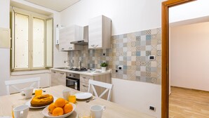 Una cocina moderna con armarios blancos, salpicadero de azulejos y un comedor con una mesa dispuesta para el desayuno.