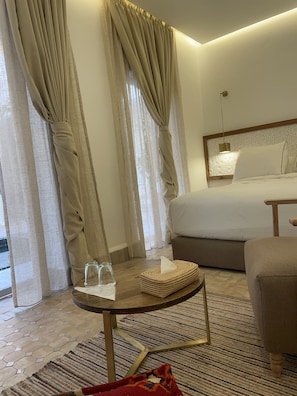 Une chambre d’hôtel avec un lit, une table ronde avec des verres et une boîte de mouchoirs, une chaise et un tapis à motifs.