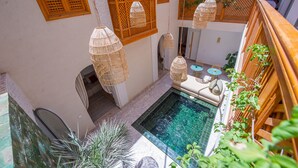 A rooftop pool area with hanging wicker lamps, a small seating area, and wooden lattice walls. - Riad Dar Bayane (Marrakech)