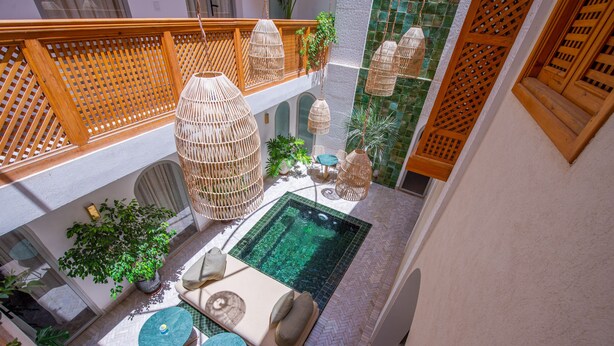 A rooftop pool area with a seating arrangement, hanging wicker lamps, and a view of the pool. - Riad Dar Bayane (Marrakech)