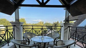 A covered outdoor seating area with a table and chairs, a view of the sky and trees, and a railing. - Stunning 2-bed Apartment in sea Resort Varna (Varna)