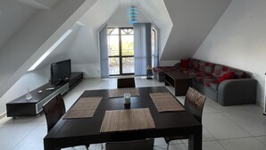 A modern loft-style living space with a dining area, a sofa, and a television. - Stunning 2-bed Apartment in sea Resort Varna (Varna)
