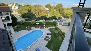 A residential area with a swimming pool, lounge chairs, and a view of surrounding buildings and trees. - Stunning 2-bed Apartment in sea Resort Varna (Varna)
