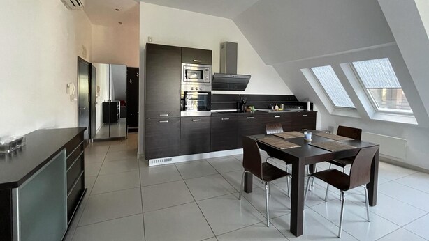 A modern kitchen with a dining area, featuring a central island, dark cabinetry, and a skylight. - Stunning 2-bed Apartment in sea Resort Varna (Varna)