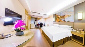 A hotel room with a bed, a desk with a lamp, a TV, and a painting on the wall. - Vienna International Hotel (Gaoxin Keji Road Metro Station Store) (Xi'an)