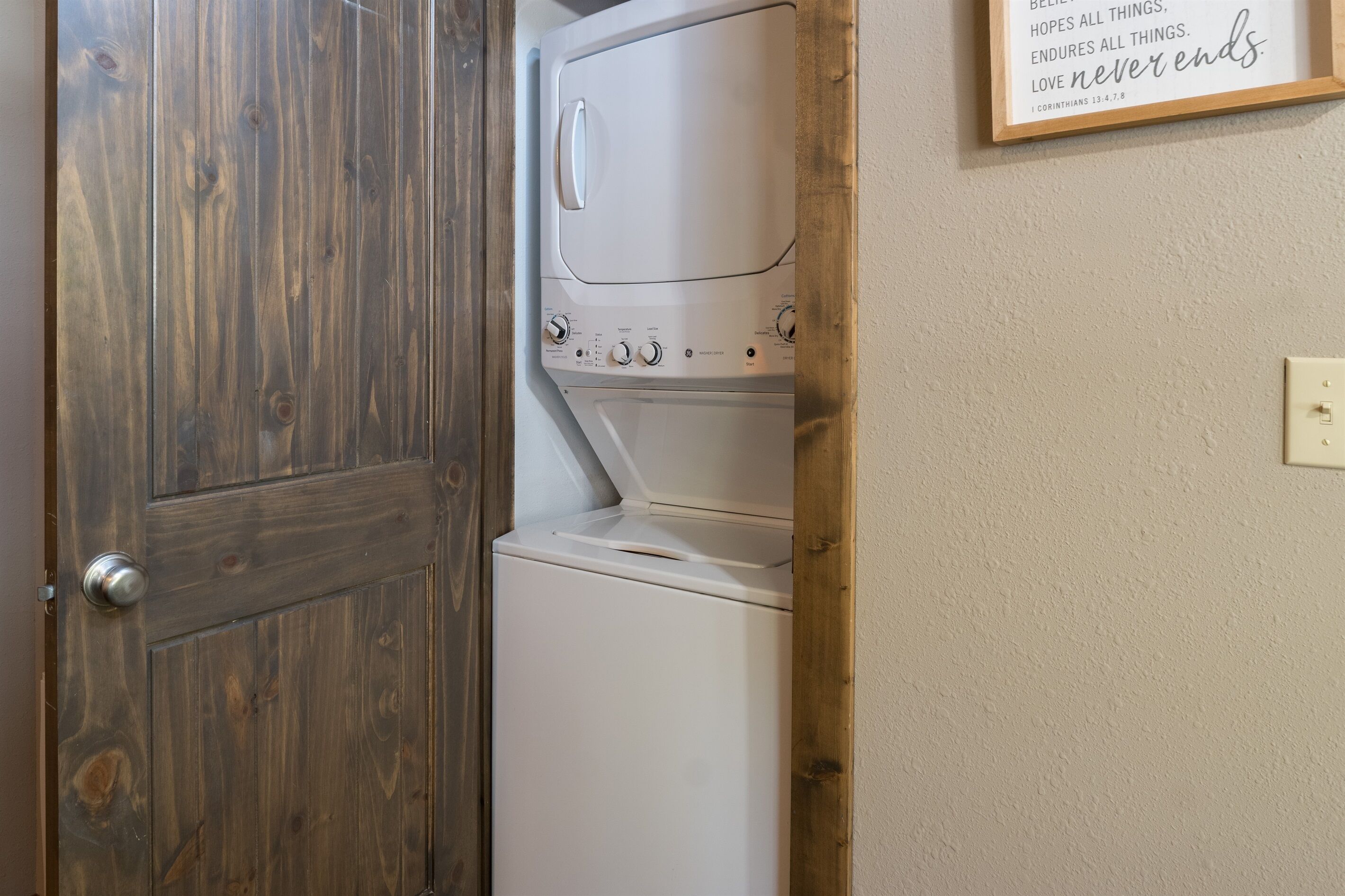 Une buanderie avec une porte en bois et un lave-linge fixé au mur.