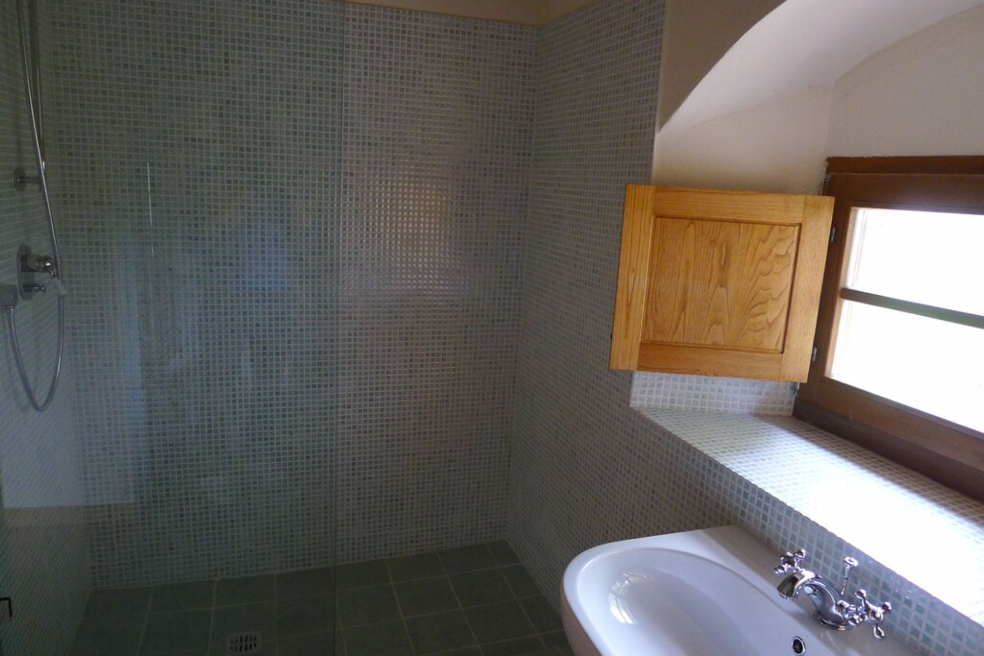 Une salle de bain avec une douche, un lavabo et un meuble en bois au-dessus du lavabo.