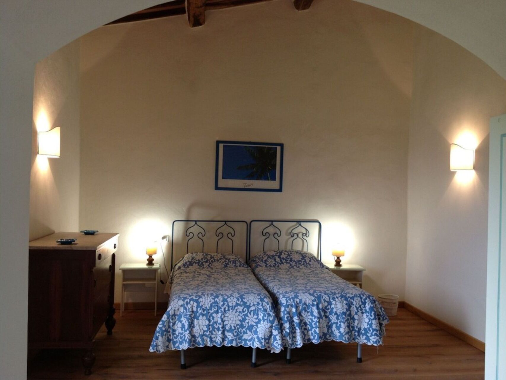 A bedroom with two beds, a desk, and two bedside lamps.