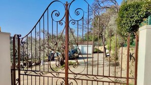 A gated entrance with a metal gate featuring decorative scrollwork. - Gite des écureuils, sea view, private pool, parking, air conditioning (La Ciotat)