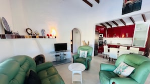 A living room with green sofas, a TV, and a small white table.