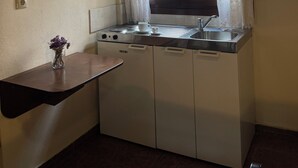 Een kleine keuken met raam, een spoelbakje en een fornuis.