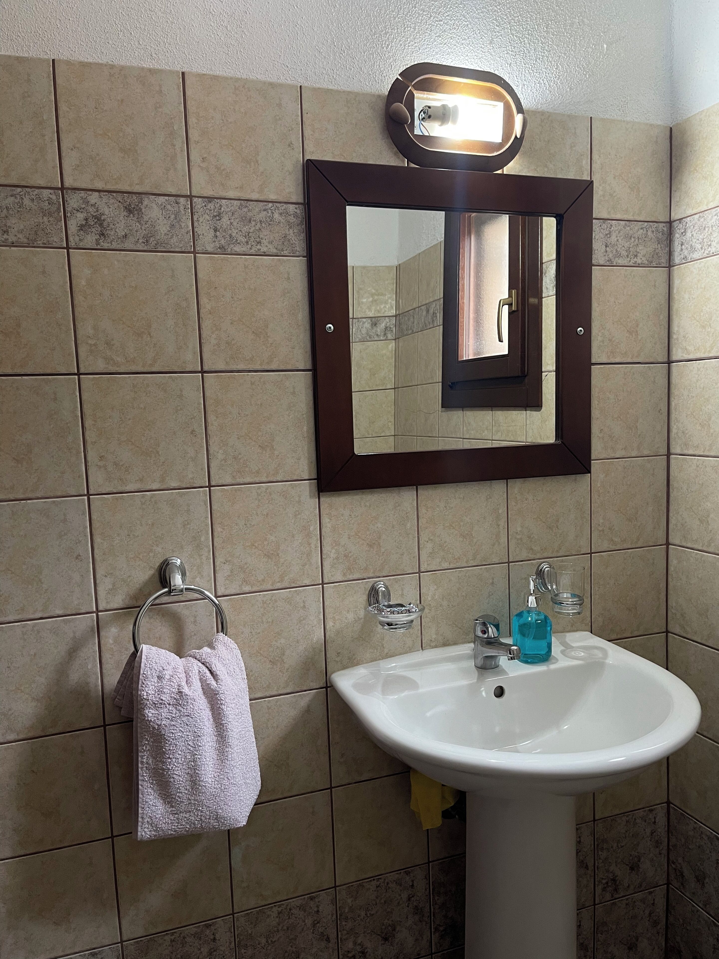 Une salle de bain avec un lavabo blanc, un miroir et un porte-serviettes.