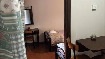 A room with a bed, a table, a chair, and a window.