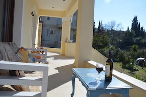A balcony with a table, a bottle of wine, and a glass of wine.