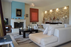 A living room with a fireplace, a sofa set, a coffee table, and a stone wall with artwork.
