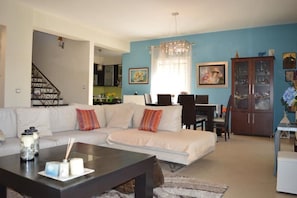 A living room with a sofa, coffee table, and a dining area with chairs and a cabinet.