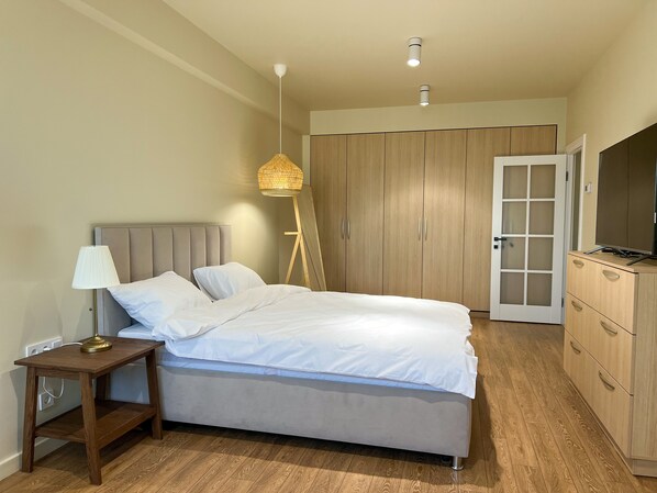 Une chambre à coucher comprenant un lit, une table de chevet, une lampe, une armoire et un téléviseur.