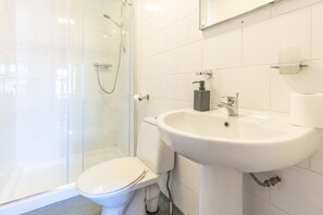 A bathroom with a glass-enclosed shower, a white toilet, and a sink with a soap dispenser. - Bloomfield 10 (Lancaster)