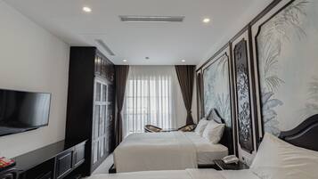 A hotel room with two beds, a flat-screen TV, a minibar, and a large window with curtains.