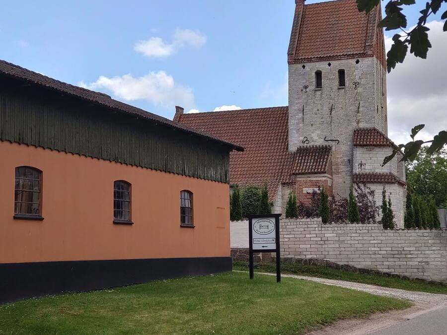 A building with a brick tower and a sign indicating a cafe and breakfast.