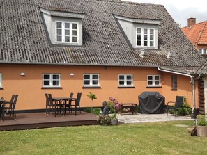 A house with a sloped roof, multiple windows, a patio with a table and chairs, and a small garden area. - Akaciegaarden Bed & Breakfast (Harlev)