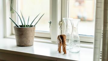 A window sill with a potted plant, a clear glass bottle, and a small wooden elephant figurine.