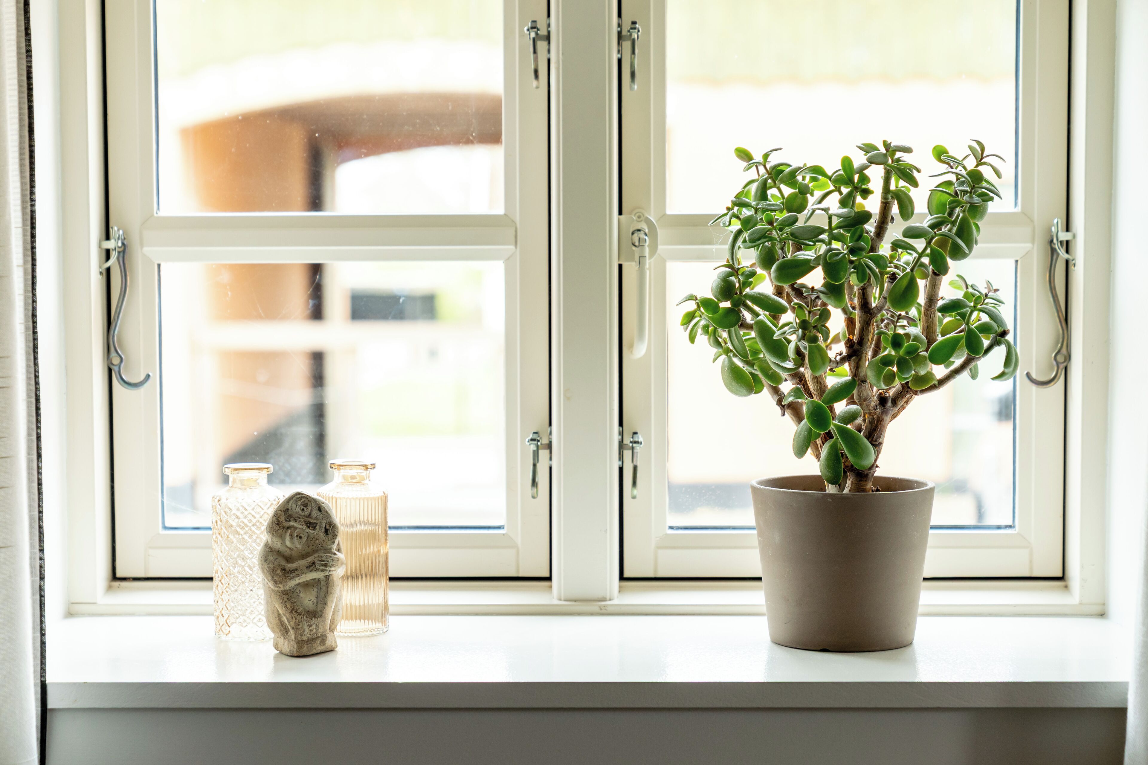 A window with a potted plant and two decorative items on the sill.