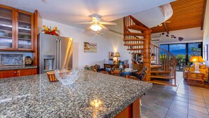 Una cocina con encimeras de granito, un refrigerador de acero inoxidable y un ventilador de techo.